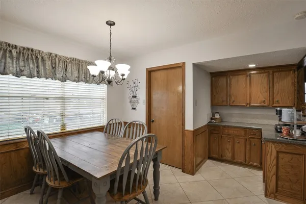 a dining room filled chandelier and kitchen view