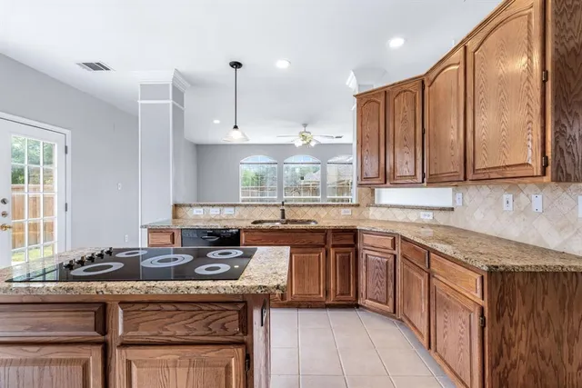 a kitchen with stainless steel appliances granite countertop a stove a sink dishwasher and a microwave oven with large wooden cabinets