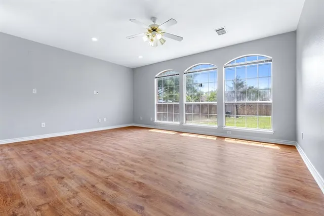 a view of an empty room with a window and wooden floor