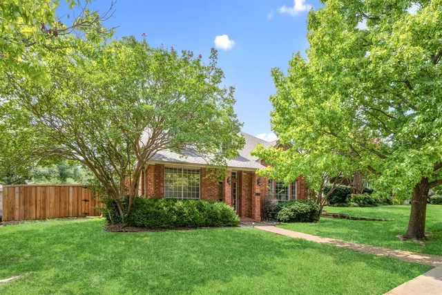 a view of a house with a big yard and large trees