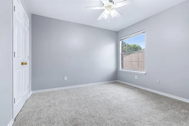 an empty room with windows and chandelier fan