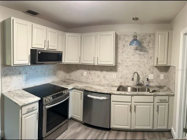 a kitchen with stainless steel appliances granite countertop a stove a sink and a refrigerator