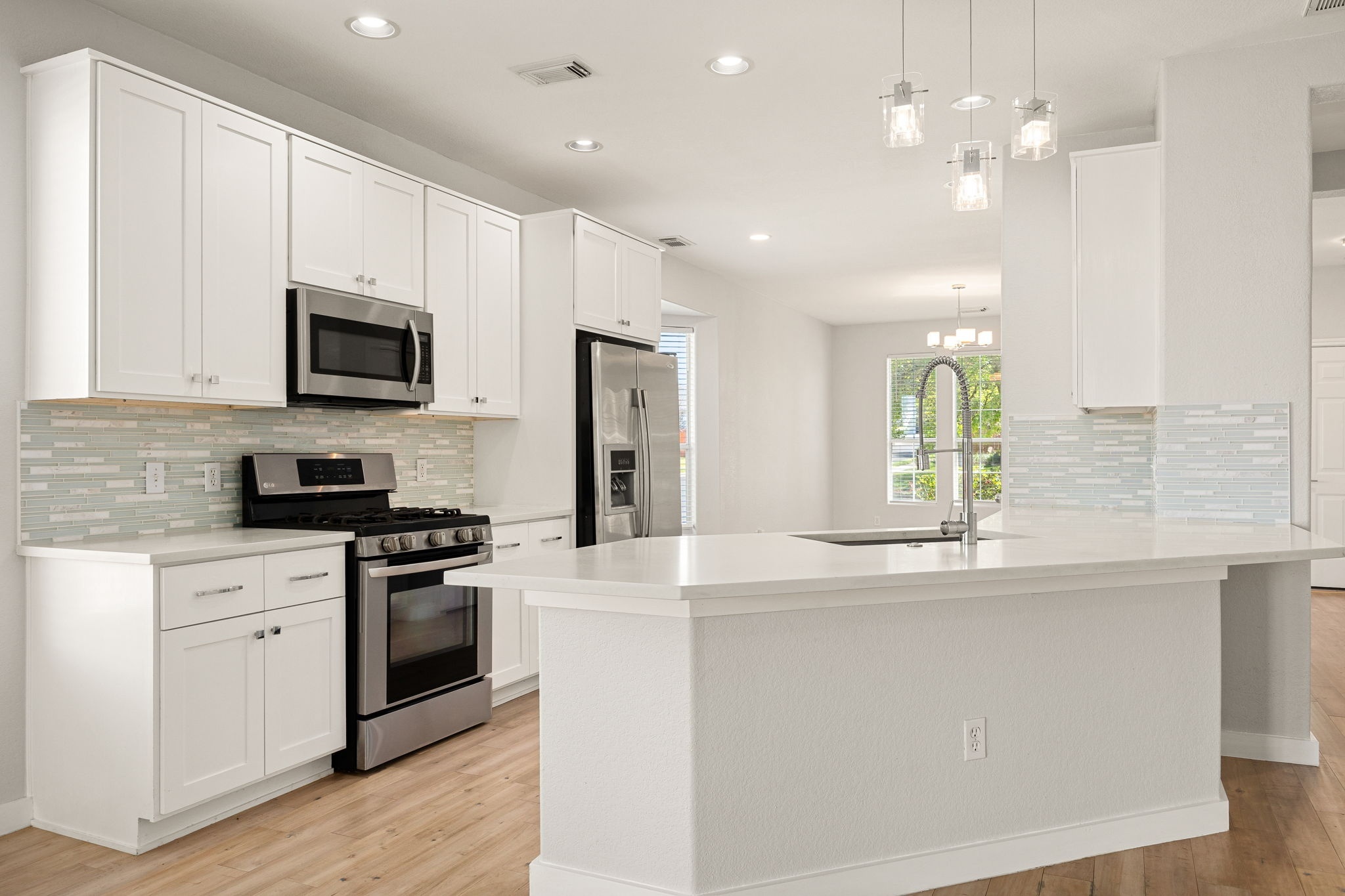 a kitchen with stainless steel appliances granite countertop a stove a sink and a microwave