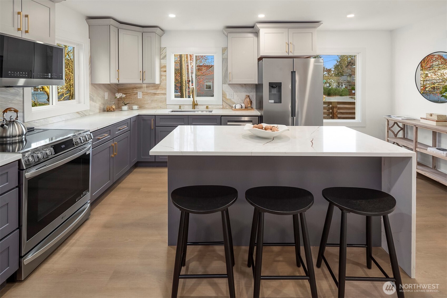 1016 Northwest 85th Street Seattle, WA 98117 - Photo 11 of 36 a kitchen with stainless steel appliances granite countertop a sink a stove a refrigerator cabinets and a dining table with wooden floor