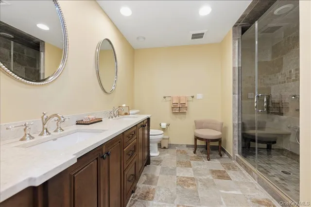 a spacious bathroom with a double vanity sink toilet and shower