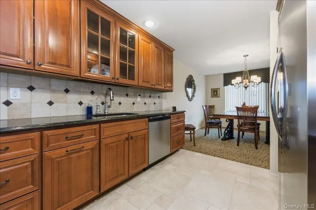 a kitchen with stainless steel appliances granite countertop wooden cabinets a dining table and chairs