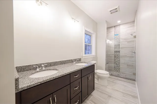 a bathroom with a granite countertop sink a toilet and shower