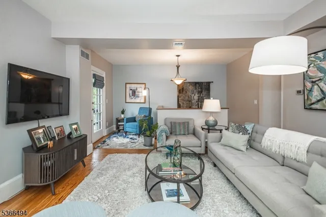 a living room with furniture a flat screen tv and wooden floor