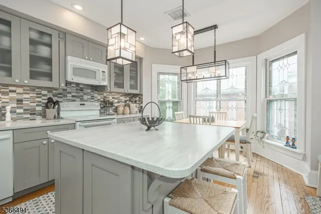 a kitchen with a table chairs refrigerator and wooden floor