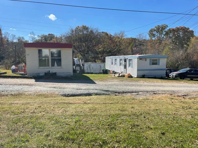 a view of a house with a big yard and large trees