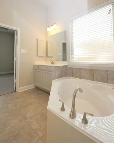 a spacious bathroom with a bathtub a sink and a window