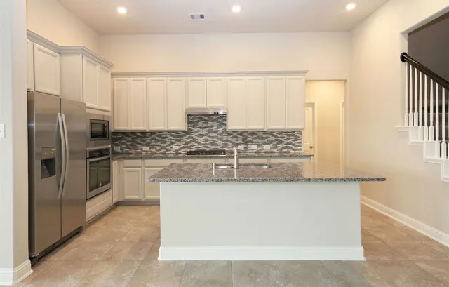 a kitchen with stainless steel appliances granite countertop a refrigerator and a sink