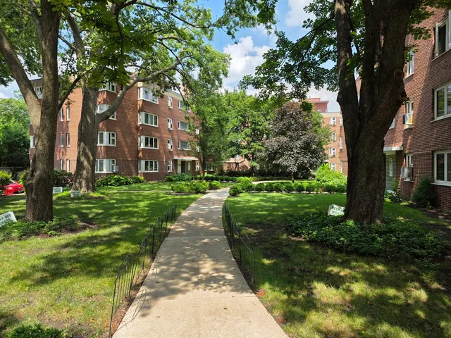 a view of a brick house next to a yard with big trees