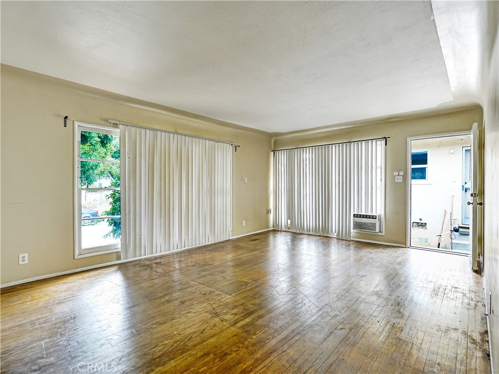 7928 Milton Avenue Whittier, CA 90602 - Photo 15 of 27 an empty room with wooden floor and windows with curtains view