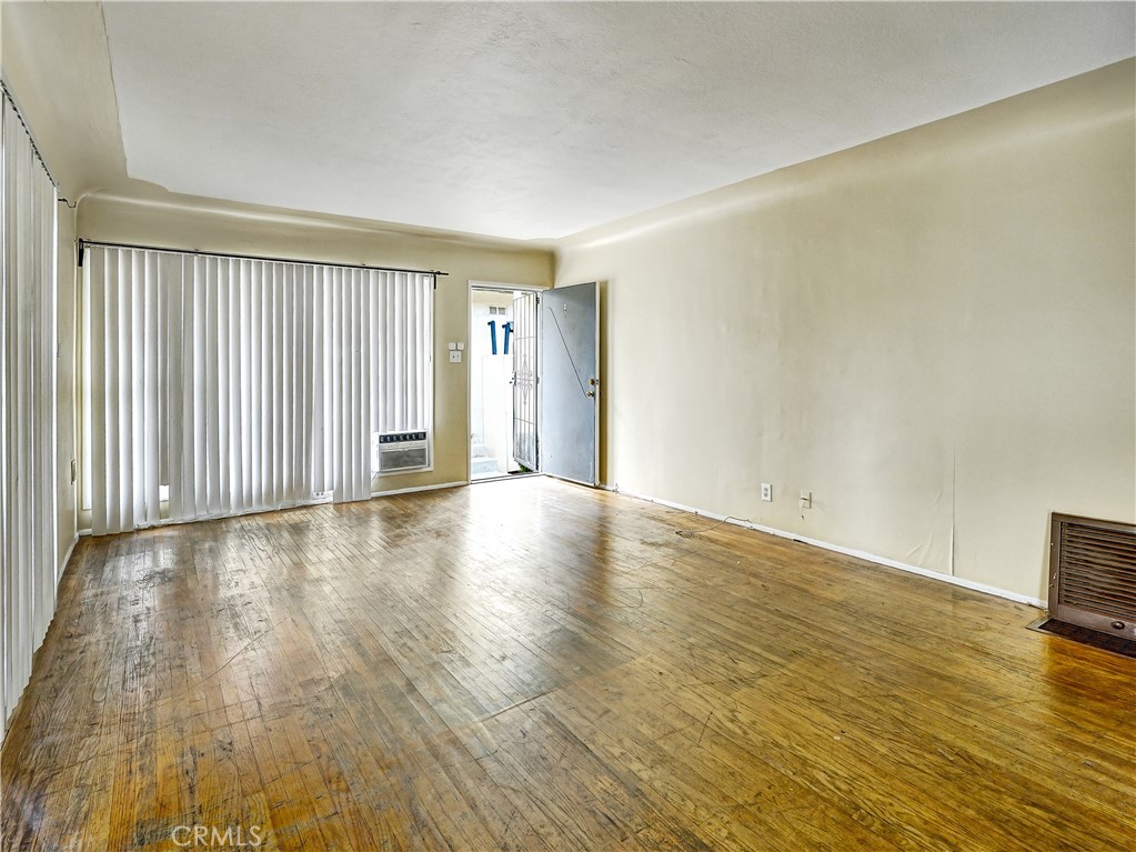 7928 Milton Avenue Whittier, CA 90602 - Photo 18 of 27 an empty room with wooden floor and windows with curtains