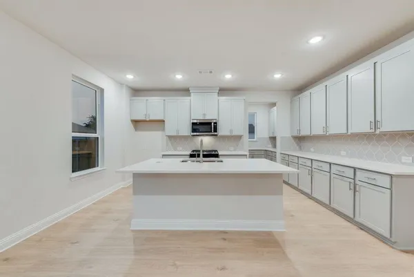 a kitchen with stainless steel appliances granite countertop a stove top oven a sink and a refrigerator