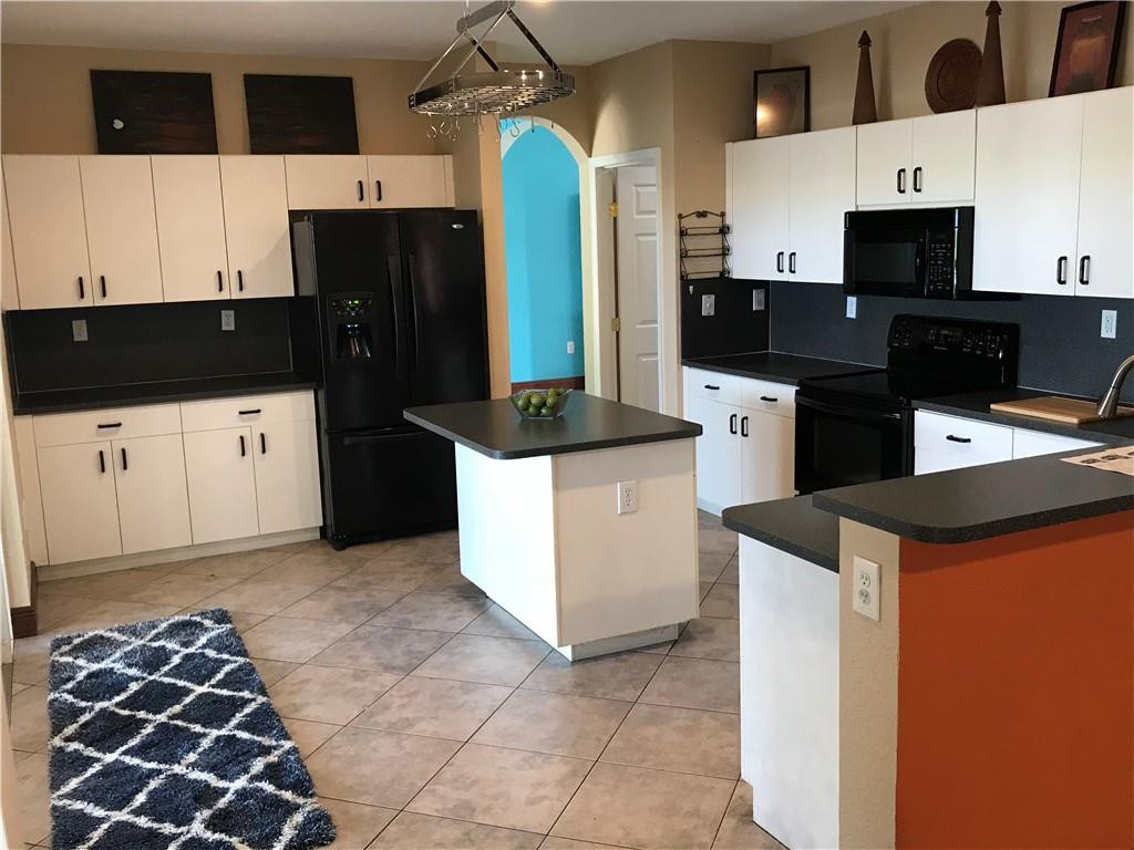 15038 Southwest 161st Place Miami, FL 33196 - Photo 6 of 23 a kitchen with stainless steel appliances kitchen island granite countertop a refrigerator and a stove top oven