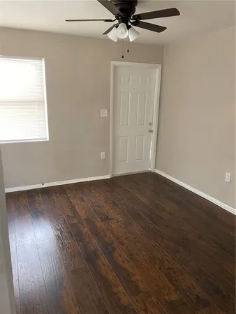 an empty room with wooden floor a ceiling fan and windows