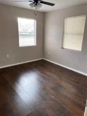 an empty room with wooden floor and windows