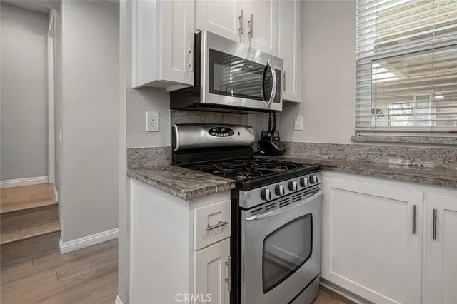 a kitchen with granite countertop white cabinets stainless steel appliances and a sink