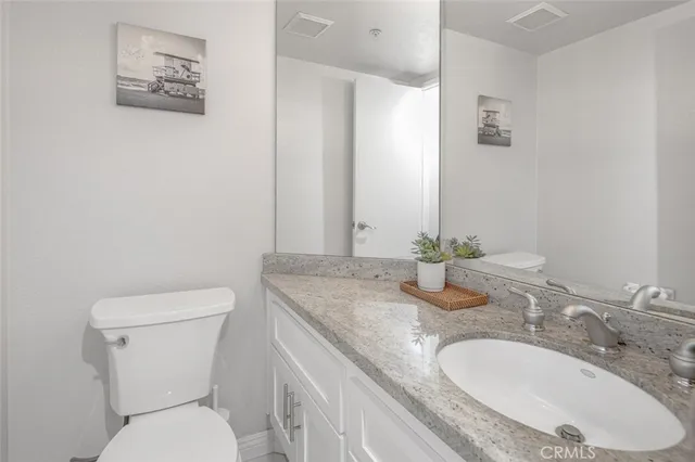 a bathroom with a granite countertop toilet sink and mirror