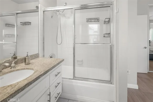 a bathroom with a granite countertop shower sink vanity and mirror