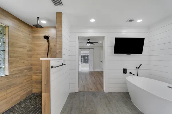 a bathroom with a bathtub and a flat screen tv
