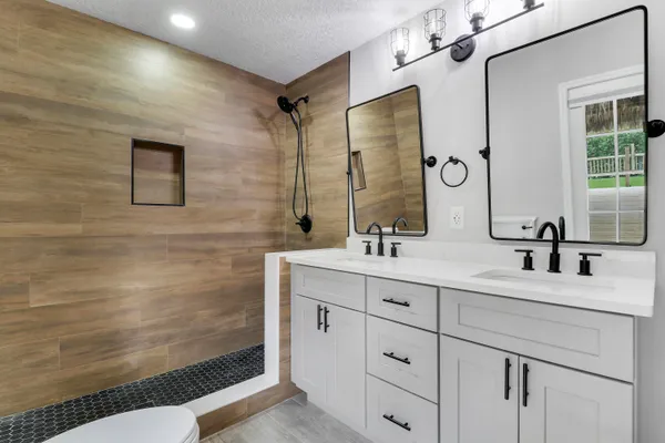 a bathroom with a double vanity sink mirror and shower