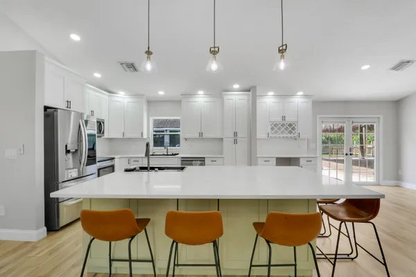 a kitchen with granite countertop a counter space chairs stainless steel appliances and cabinets