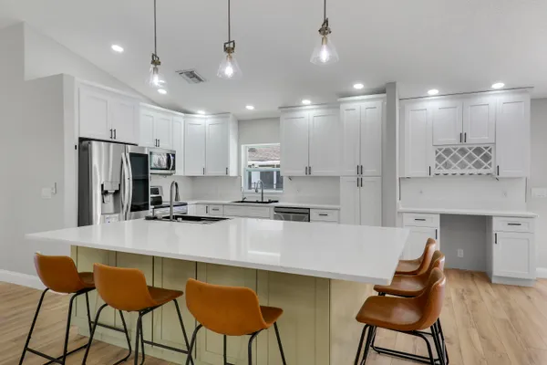 a large kitchen with kitchen island a dining table chairs stainless steel appliances and cabinets