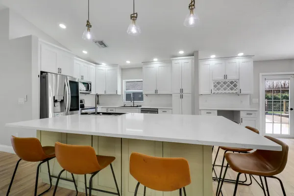 a kitchen with stainless steel appliances granite countertop a table chairs refrigerator and sink