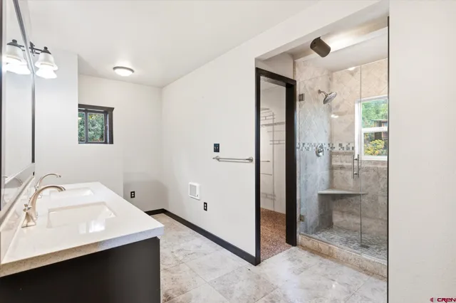 a bathroom with a sink double vanity granite tub shower and a mirror