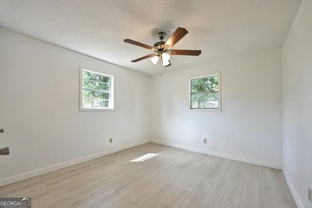 an empty room with a window and a fan