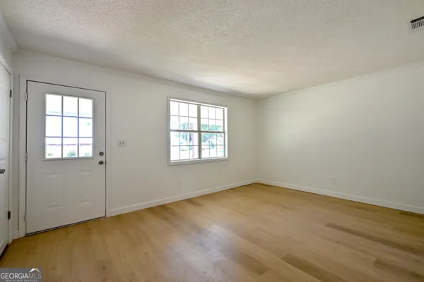an empty room with wooden floor and windows