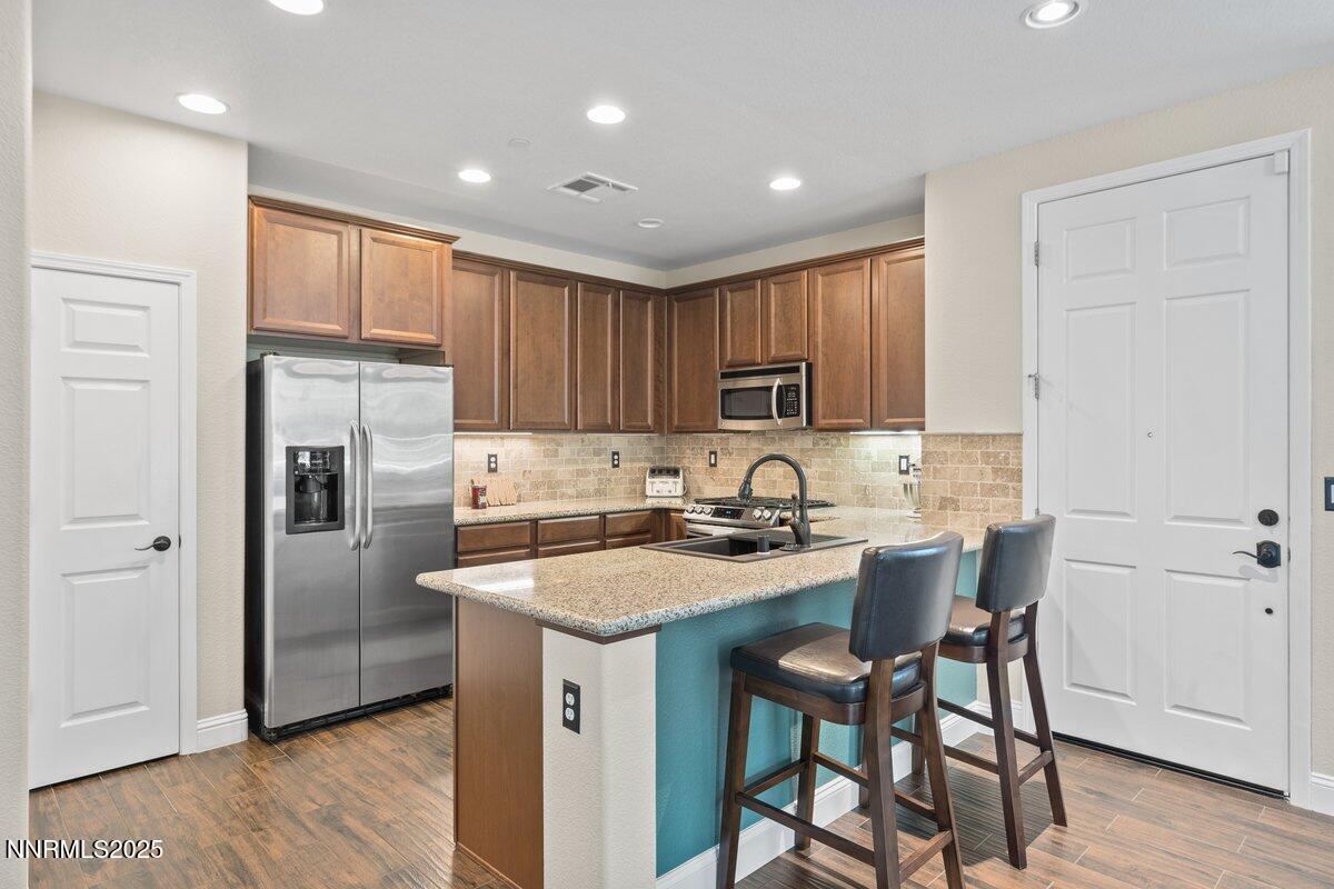 1955 Wind Ranch Road, Unit A Reno, NV 89521 - Photo 7 of 23 a kitchen with kitchen island granite countertop wooden cabinets and refrigerator