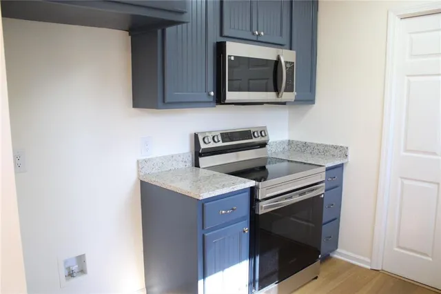 a kitchen with granite countertop cabinets stainless steel appliances and wooden floor