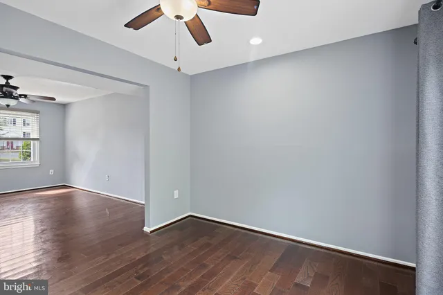 an empty room with wooden floor fan and windows