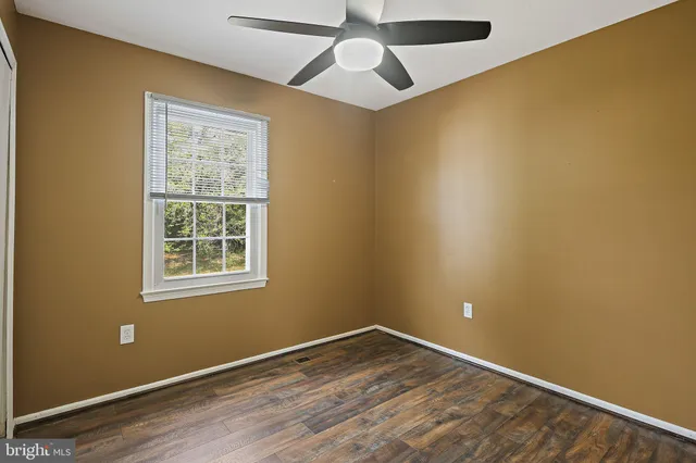 an empty room with a window and a ceiling fan