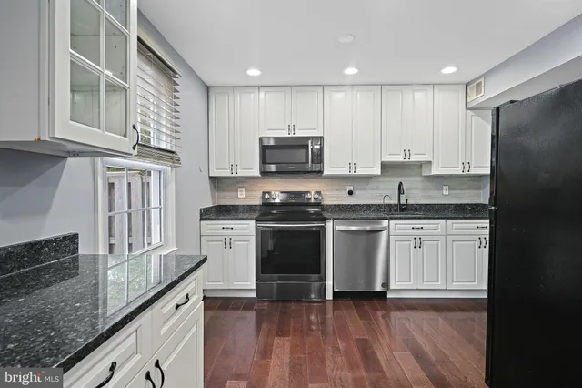 a kitchen with granite countertop a refrigerator stove top oven and sink