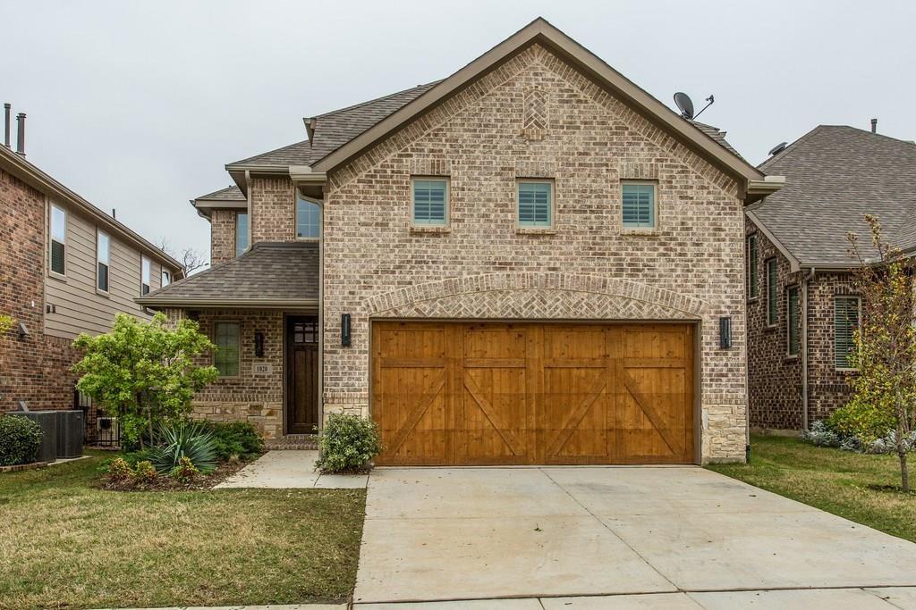 View of front of home with brick siding, a shingled roof, driveway, a front yard, and an attached garage