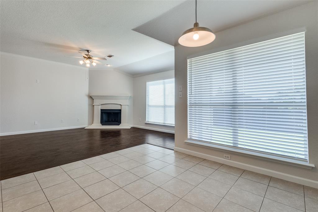 1257 Barrel Run Fort Worth, TX 76052 - Photo 9 of 26 Corner fireplace with detailed mantel, ceiling fan, wood-finish flooring, tiled flooring, and multiple large windows with blinds