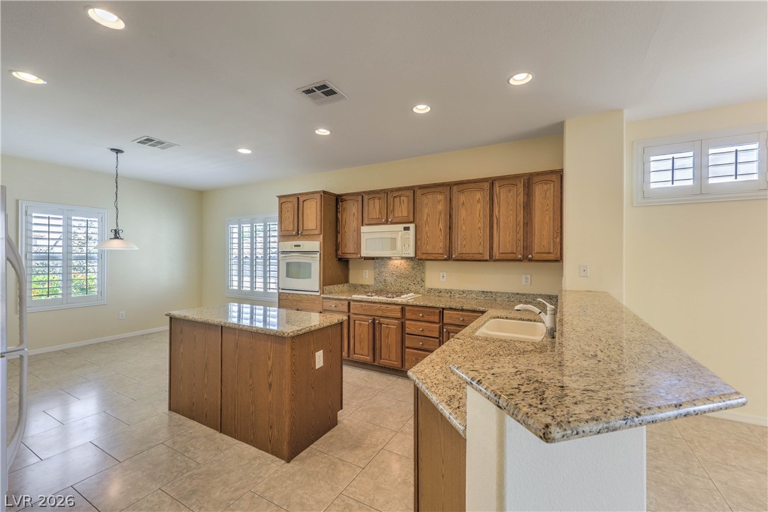 2276 Saxtons River Road Henderson, NV 89044 - Photo 9 of 49 Island Kitchen features Granite Countertops, Upgraded Cabinets w/ Pull-Out Shelves, Breakfast Bar, Nook, Pantry, Tile Flooring, Recessed Lighting, Built-In Oven w/ Convection, Gas Cooktop, Microwave, and Dishwasher