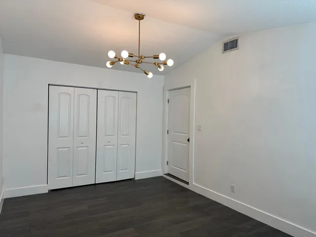 a view of an empty room with chandelier fan