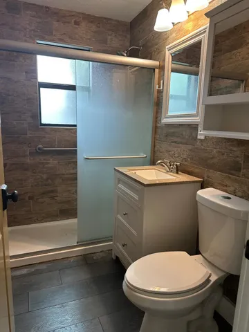 a bathroom with a granite countertop toilet a sink and a mirror