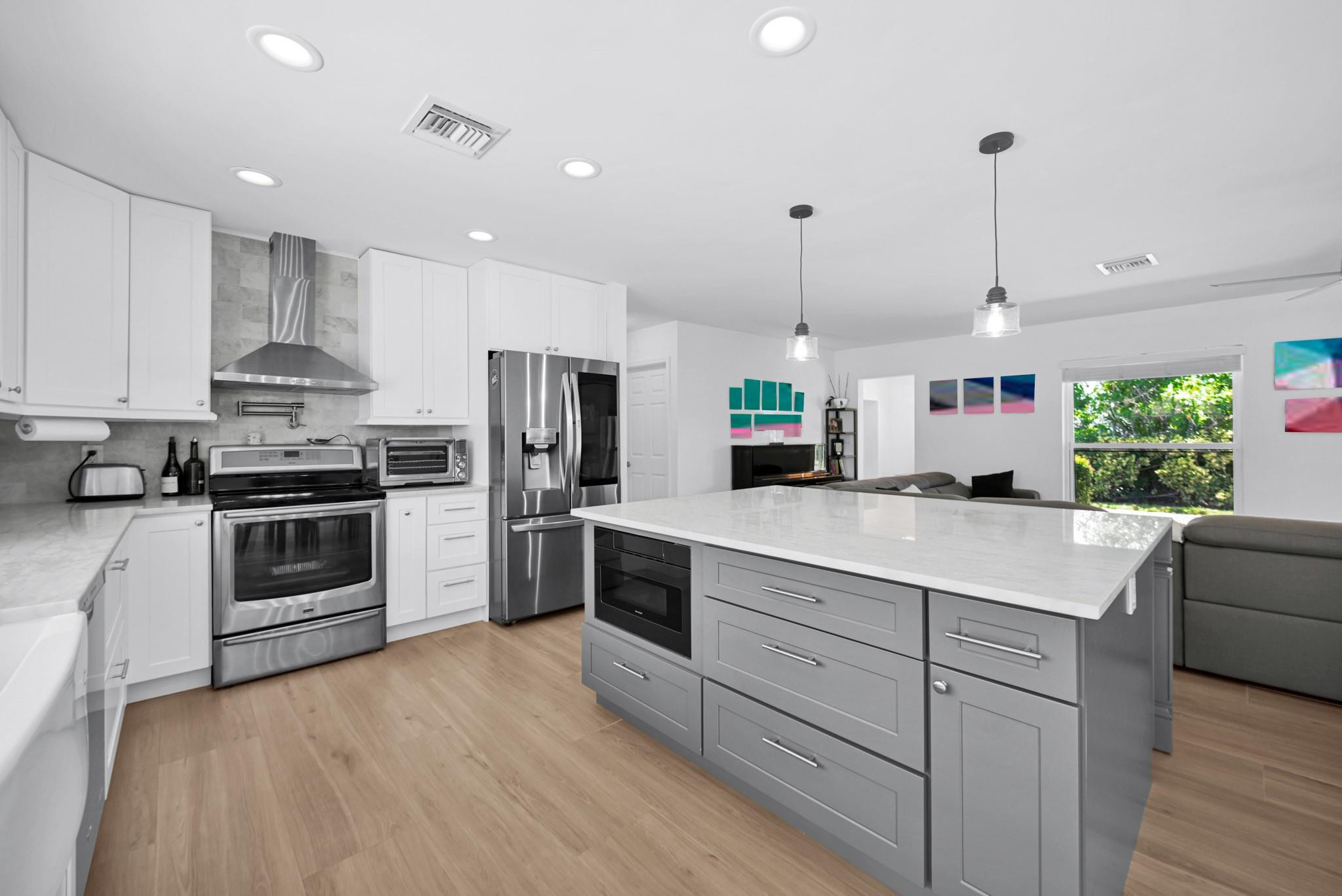 252 Southwest 14th Place Boca Raton, FL 33432 - Photo 13 of 49 a kitchen with stainless steel appliances kitchen island granite countertop a stove a sink and a refrigerator with wooden floor