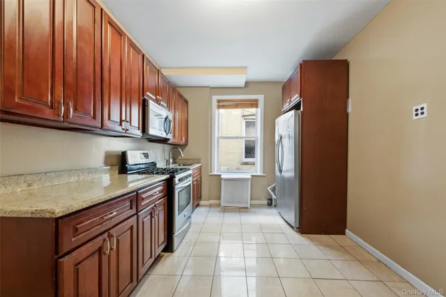 a kitchen with stainless steel appliances granite countertop a stove a sink dishwasher and a refrigerator with wooden cabinets