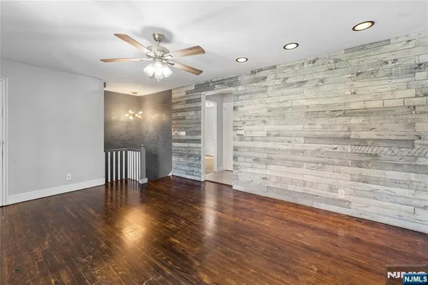 a view of an empty room with wooden floor and a ceiling fan