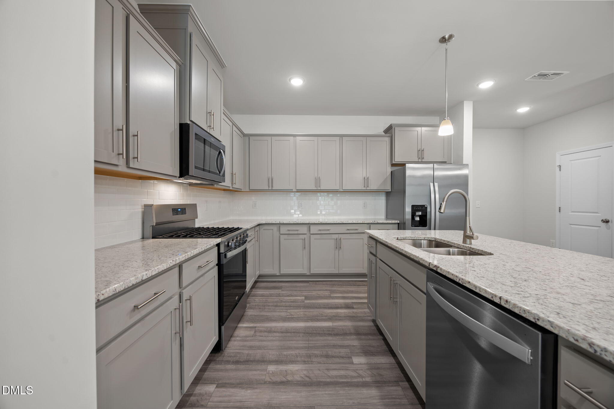 202 Fosterton Cottage Way Raleigh, NC 27603 - Photo 3 of 13 a kitchen with kitchen island granite countertop a sink and stove top oven