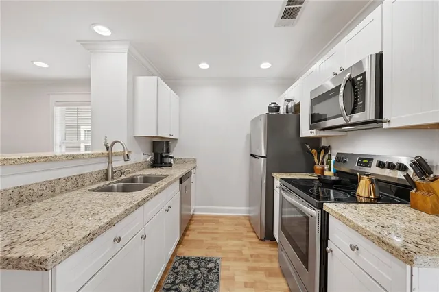 a kitchen with granite countertop a sink stainless steel appliances and cabinets