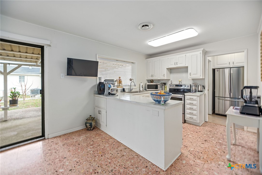 207 Williams Street Tivoli, TX 77990 - Photo 13 of 32 a kitchen with white cabinets and stainless steel appliances